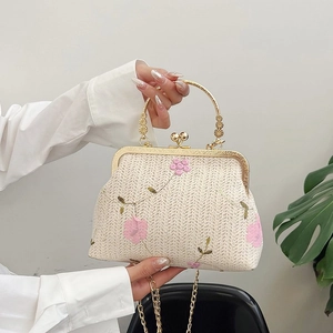 Detail of woven straw handbag with pink floral embroidery and vintage gold handle