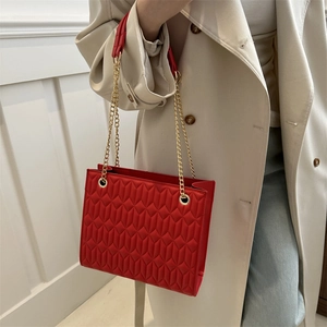 Red quilted leather chain crossbody bag with gold hardware worn on a beige trench coat