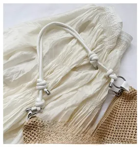 Detail of hand-woven straw tote with white rope handles and silver zipper closure