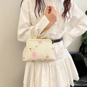 Detail of beige woven clutch with pink floral embroidery and gold metal chain strap