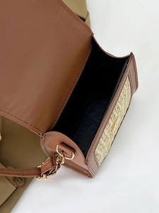 Brown leather and straw woven crossbody bag shown from above in a fashion setting