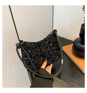 Detailed close-up of a crescent-shaped shoulder bag with shimmering black sequins and zipper
