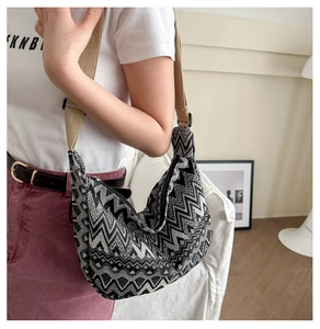 Details der Retro-Stricktasche mit schwarz-weißen Wellenmustern und khaki Schultergurt