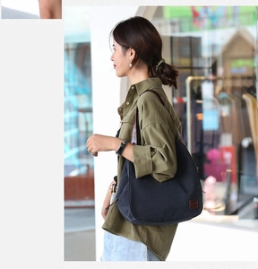 Gros plan sur un sac hobo noir en toile avec bandoulière en cuir brun porté en style urbain
