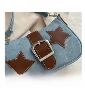 Detailed view of denim shoulder bag featuring star patches and a silver metal buckle strap
