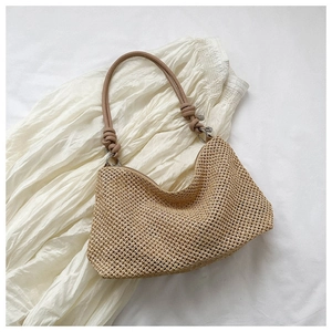 Detail shot of handwoven straw tote with thick leather handles on white fabric