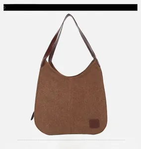 Détail du sac hobo en toile marron avec bandoulière en cuir et patch logo embossé