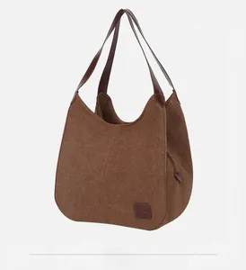 Vue latérale du grand sac cabas en toile marron avec anses en cuir et coutures renforcées