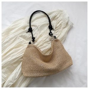 Detailed view of handmade woven straw tote bag with black braided strap and zipper closure