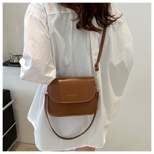 Détail de la sacoche bandoulière en cuir marron avec sangle réglable sur le mannequin