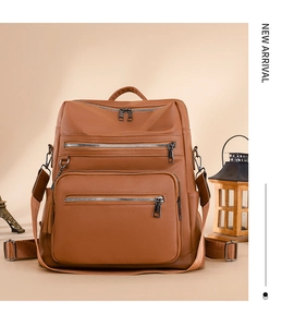 Detail of brown lychee grain leather backpack featuring triple front zippers and bronze hardware