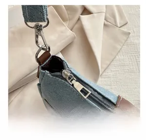 Detailed close-up of smooth silver metal zipper and hardware on light blue denim bag