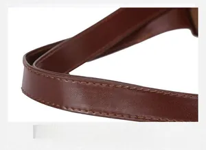 Détail de la poignée en cuir marron avec coutures de précision et finition soignée
