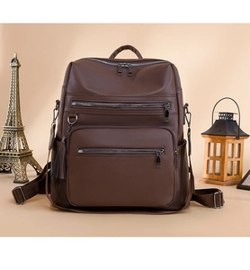 Detail of dark brown leather backpack with tassel charms and multi-zipper compartments