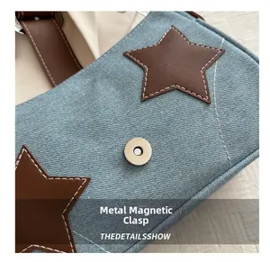Detail of denim shoulder bag featuring star leather patch and silver magnetic buckle