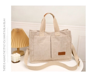 Detail of beige corduroy tote bag showing front pockets and brown fashion leather label