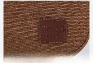 Vue macro détaillée de l'écusson logo en cuir sur un sac à bandoulière en toile marron