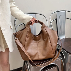 Detail of a brown PU leather hobo tote bag with soft texture on a metallic chair