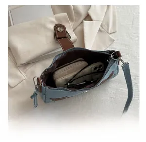 Detail view of denim underarm bag showing space for phone, wallet and sunglasses
