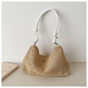 Detail of hand-woven straw hobo bag featuring white knotted handle and silver metal rings