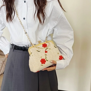 Detail of cream woven crossbody bag with red flower embroidery and gold chain strap