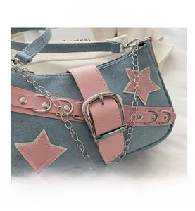 Macro view of blue denim underarm bag featuring pink stars and bold silver metal buckle