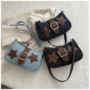 Three denim underarm bags in blue and black with brown leather stars and metal buckles