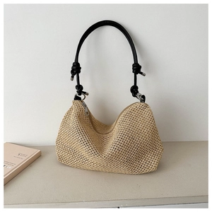 Detail of hand-woven straw hobo bag with black leather knot handle and metal zipper closure