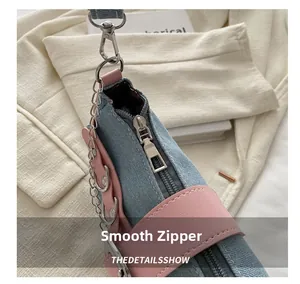 Detail of smooth silver metal zipper and pink leather trim on denim shoulder bag