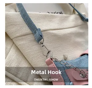 Detail of silver hardware hook and denim shoulder strap with pink leather on women bag