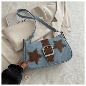 Detail of light blue denim shoulder bag with brown star patches and metal buckle decor