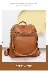 Close-up of brown leather travel backpack featuring metal chains and tassel charms