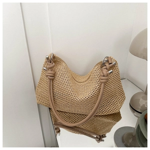 Detail of khaki straw crescent bag with knotted leather strap on a reflective surface