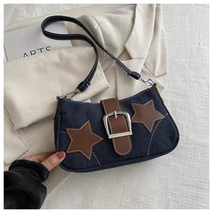 Detail of denim shoulder bag with leather star patches and metallic buckle closures