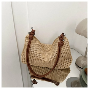 Detailed texture of straw shoulder bag with brown leather strap and silver metal caps