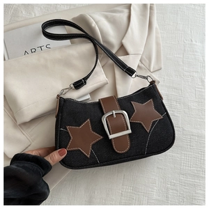 Detailed close-up of brown leather star patches and metal buckle on black denim bag