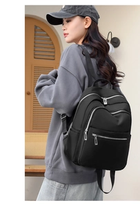 Side view of a large black waterproof nylon backpack with multiple silver zippers
