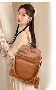 Close-up of brown leather backpack featuring multiple zippers and a stylish leather tassel