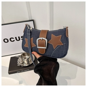 Detail of dark blue denim shoulder bag featuring star appliques and large metal buckle