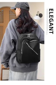 Detail of the black nylon backpack with multiple silver zippers shown from a back view