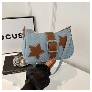 Close-up of blue denim underarm bag with brown star patches and silver metal buckle