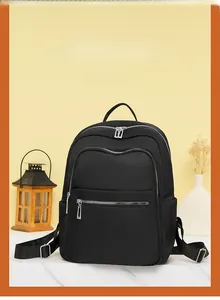Detail view of black nylon backpack featuring dual front zipper pockets and side pockets