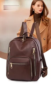 Detail of dark brown leather backpack featuring multi-layer compartments and gold zippers