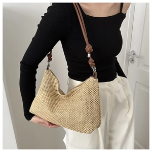 Close-up of beige woven straw shoulder bag with brown leather knotted strap detail