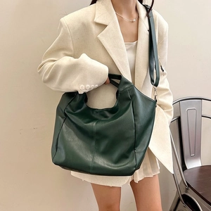 Detail of dark green large hobo bag with leather texture and shoulder strap on model