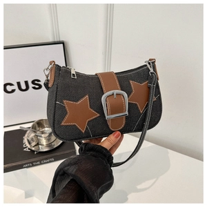 Detailed shot of black denim bag featuring brown leather star patches and metal buckle