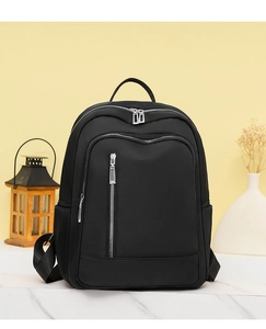 Waterproof black nylon backpack with multi-zipper compartments on a stylish desk