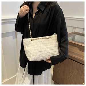 Detailed view of white tweed chain bag showing woven texture and gold metal strap