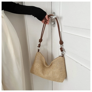 Detail of straw woven tote with brown knotted shoulder strap and metal zipper