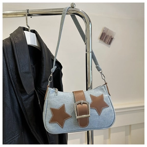 Detail of denim shoulder bag featuring brown star patches and a large silver metal buckle